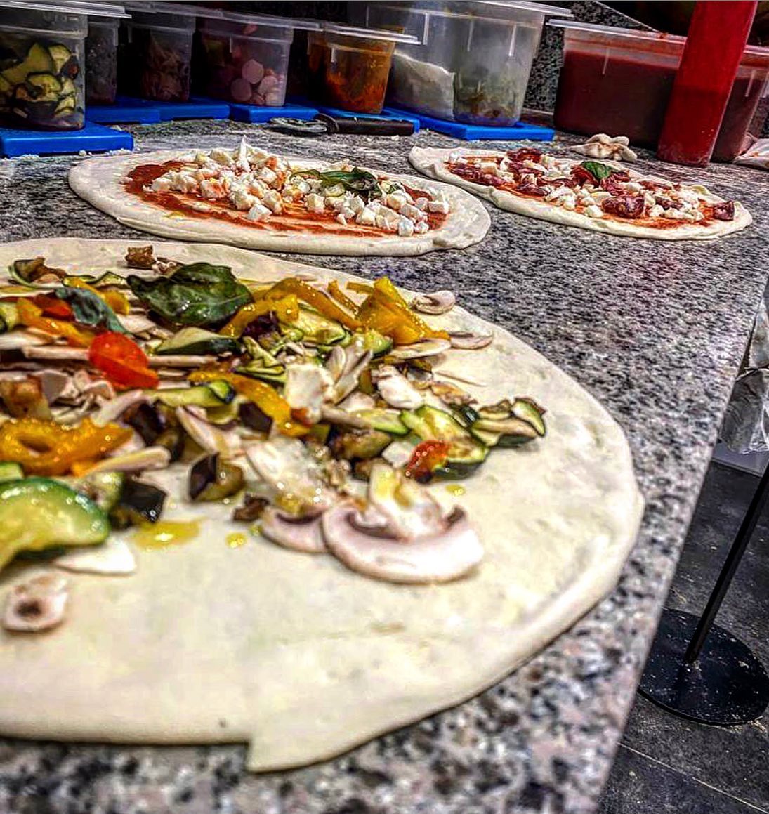 Pizze in preparazione sul bancone